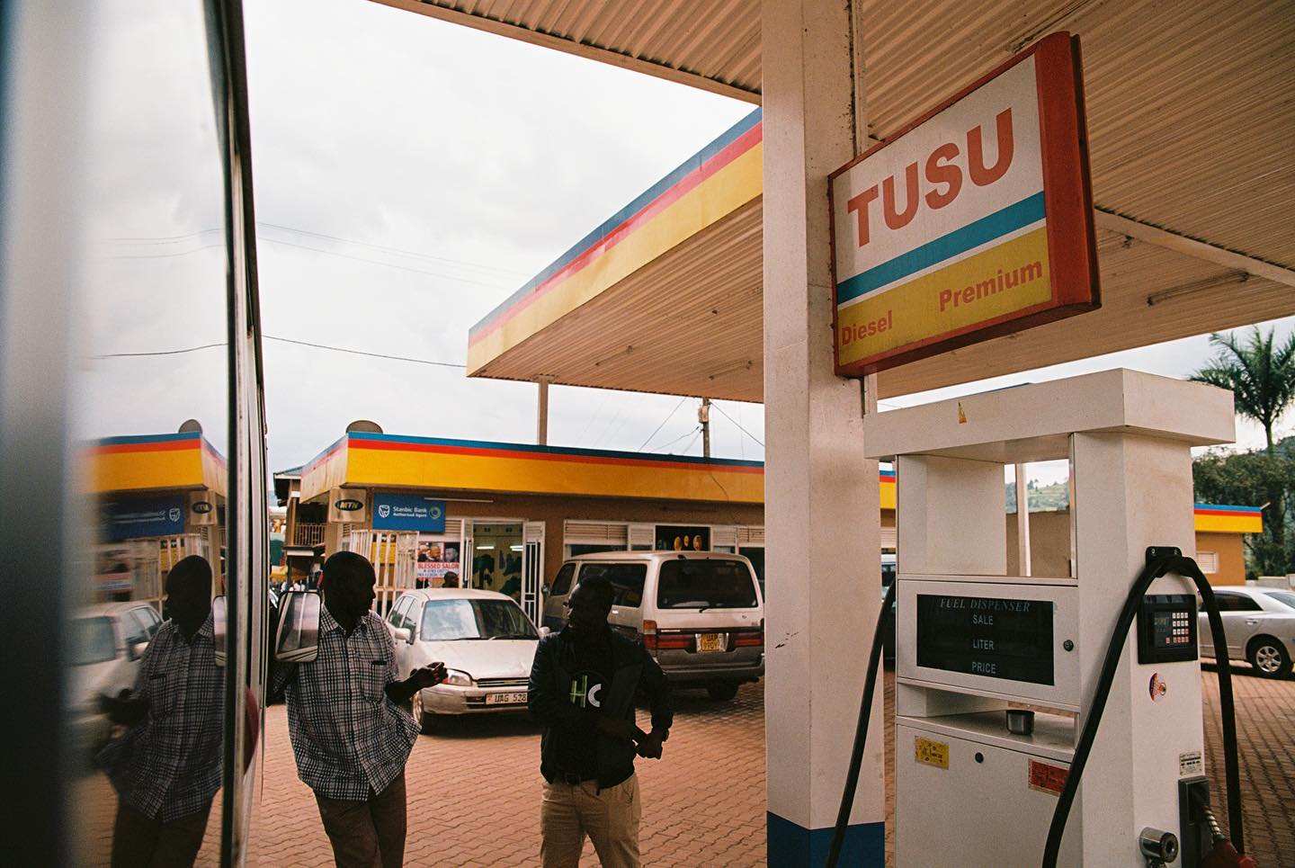 “Reflections on Gas Passed” • Kodak Ektar 100 • Canon Rebel K2 35mm • Sigma 24-70mm f2.8 ••••#uganda #gas #film #reflection #bus #overcast #africa #men #standing